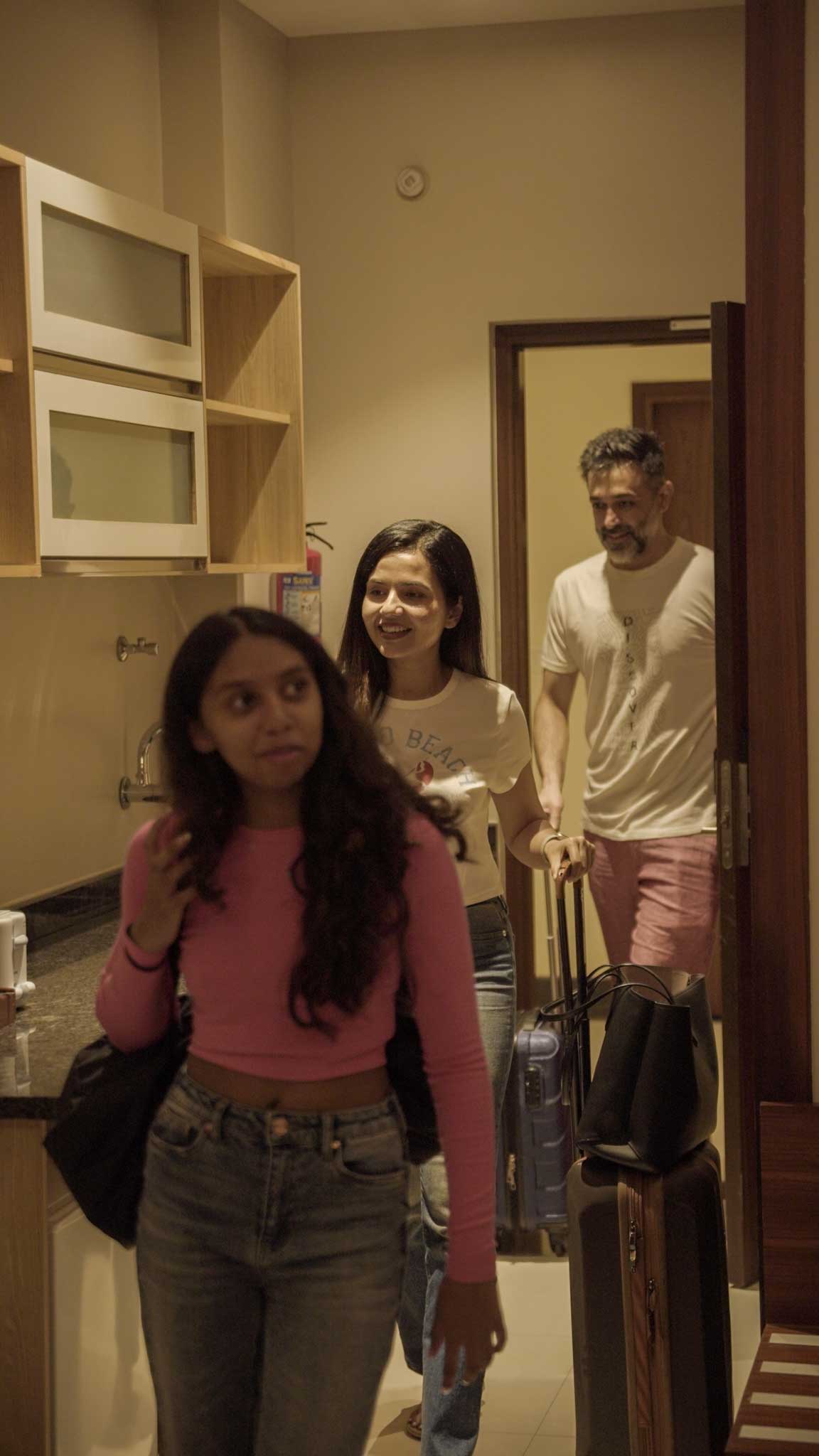 Family with luggage entering accommodation room during playcation